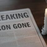 STUNNING Twist: Murder Committed By Their Own Champion… A newspaper with the headline 'BREAKING ICON GONE' next to a lit candle