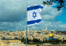 Israeli flag waving in front of the Jerusalem skyline with a golden dome in view
