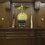 Fury Over Deceptive Kars4Kids Ads… Judges bench in an empty courtroom, scales emblem above.
