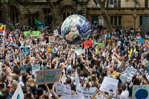 shutterstock1340782703-2jpg Crowd at climate protest holding signs and large Earth balloon.
