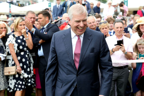 shutterstock_1469221997.jpg A man in a suit smiling crowd in background.