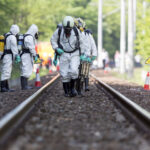 Ebola PANIC: WHO’s Emergency Declaration SHOCKS! Hazmat team members in protective suits working on a railway track