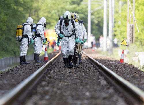 A,Team,Working,With,Toxic,Acids,And,Chemicals,Is,Approaching Hazmat team members in protective suits working on a railway track