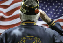 VETERAN Charged $21K for Own Benefits! Veteran saluting in front of American flag.