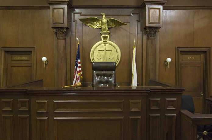 121502698-3 Judges bench in an empty courtroom, scales emblem above.