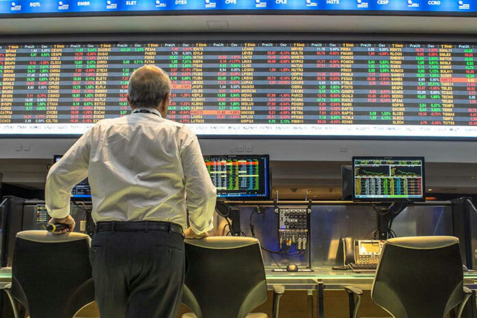391295668 Person viewing stock market data on multiple screens.