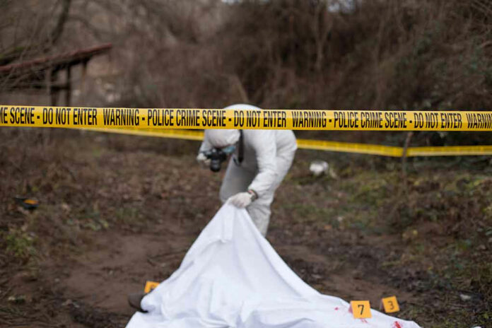 Police crime scene with investigator examining covered body