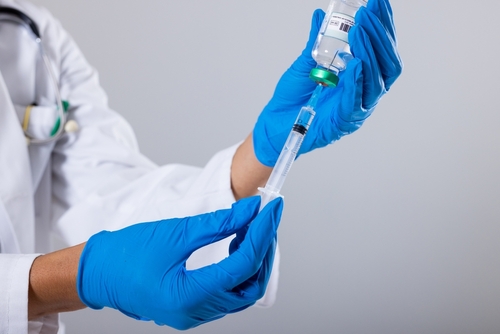 Midsection,Of,African,American,Mid,Adult,Female,Doctor,Wearing,Gloves A healthcare professional preparing a syringe with a vaccine