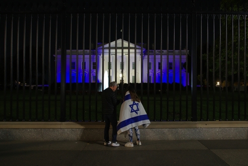 Washington,,Dc,-,October,9,,2023:,Two,People,,One,Draped A couple standing by the White House fence at night, one draped in an Israeli flag