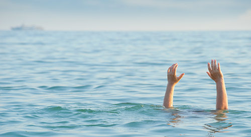 Persons hands raised above water in a distress signal