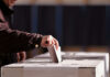 Person placing a ballot into a voting box