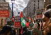 Crowd of protesters holding signs and Palestinian flags during a rally for Palestinian freedom