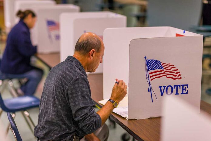 Man voting in a booth with American flag.