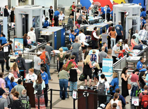 Crowd at an airport security checkpoint with TSA officers.