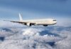 Airplane flying above the clouds, blue sky background.