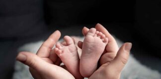 Baby feet cradled in adult hands.