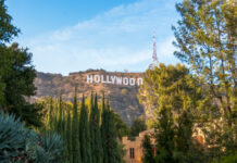 Hollywood Sign on hillside surrounded by trees, clear sky.