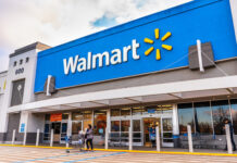 Walmart storefront with people and shopping carts outside.