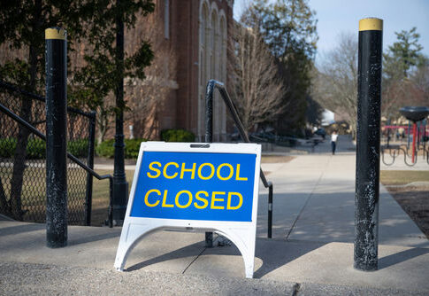 School closed sign on sidewalk near building.