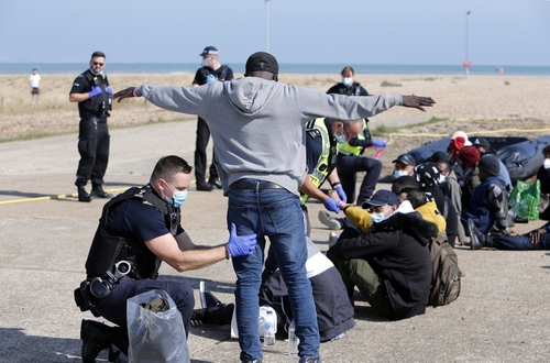 Police officers assist migrants on a beach.