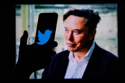 A phone with Twitter logo against Elon Musk's image.