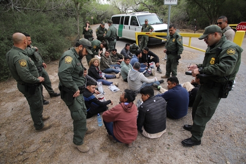 Border patrol agents detaining a group of immigrants.