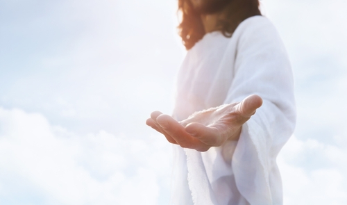 Person in white robe extending hand.