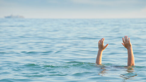 Persons hands raised above water in a distress signal